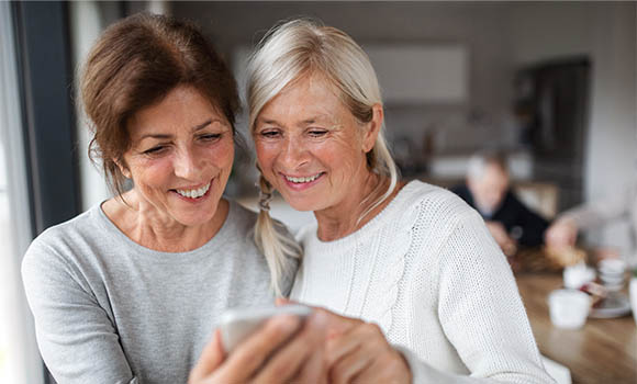 two women looking at a phone screen together and smiling